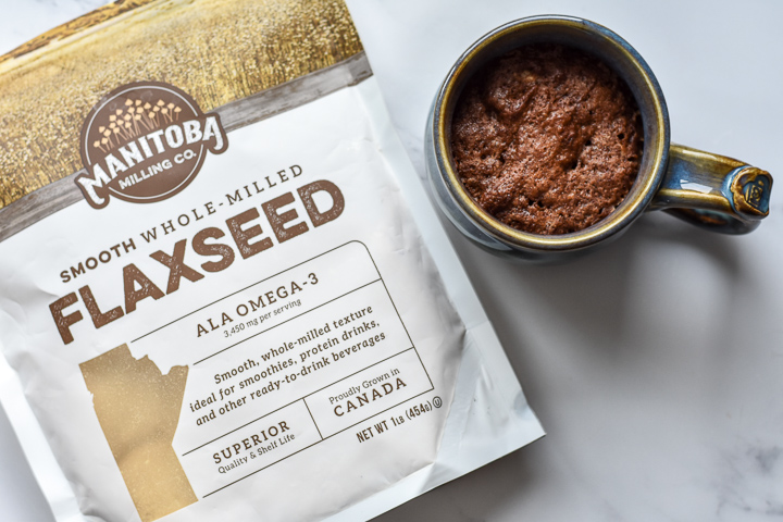 Photo of Chocolate Flaxseed Cake in a mug with a bag of Manitoba Milling Smooth Whole Milled Flaxseed