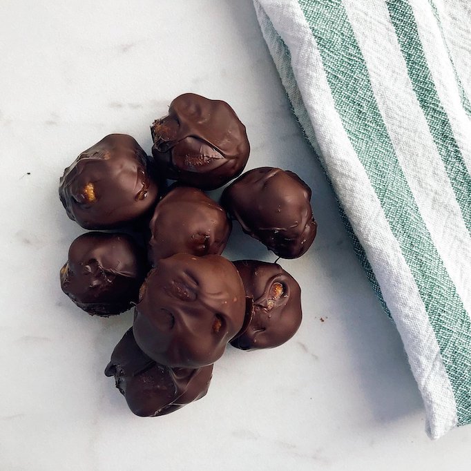 photo of chocolate covered peanut butter balls with white background and green and white striped towel