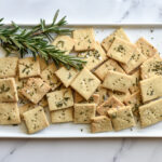 homemade flaxseed crackers pictured with rosemary on platter