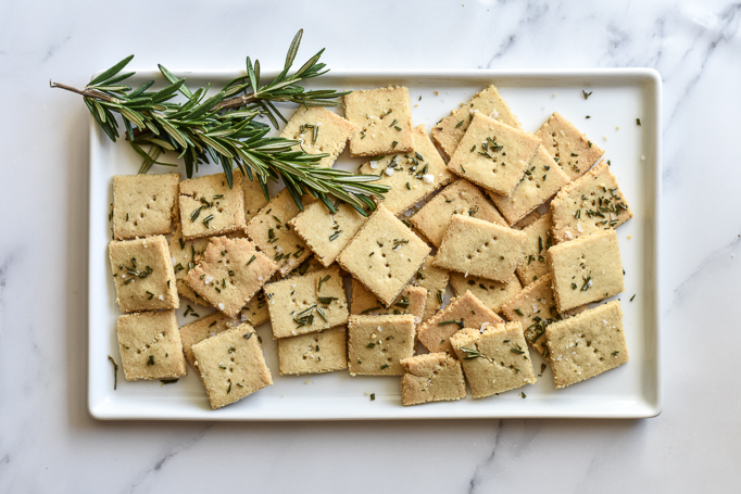 homemade flaxseed crackers pictured with rosemary on platter