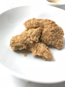 photo of homemade gluten free chicken tenders on white plate, made with flaxseed instead of breadcrumbs