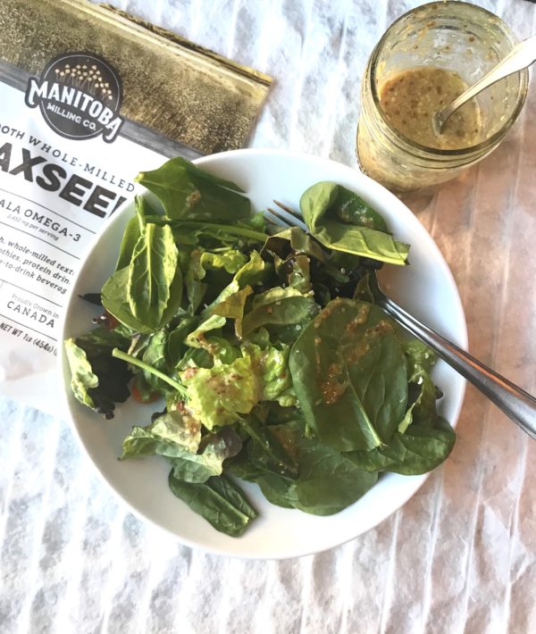 bowl of salad with dijon flax dressing on top and the jar next to it