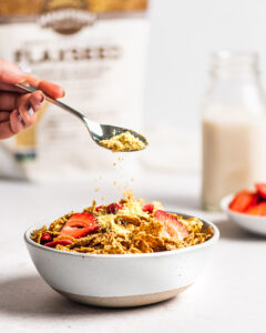 Milled Flaxseed on a spoon sprinkling over a white bowl with Cereal