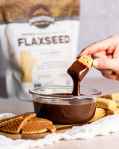 rectangular cookie dunked into chocolate sauce in a clear bowl